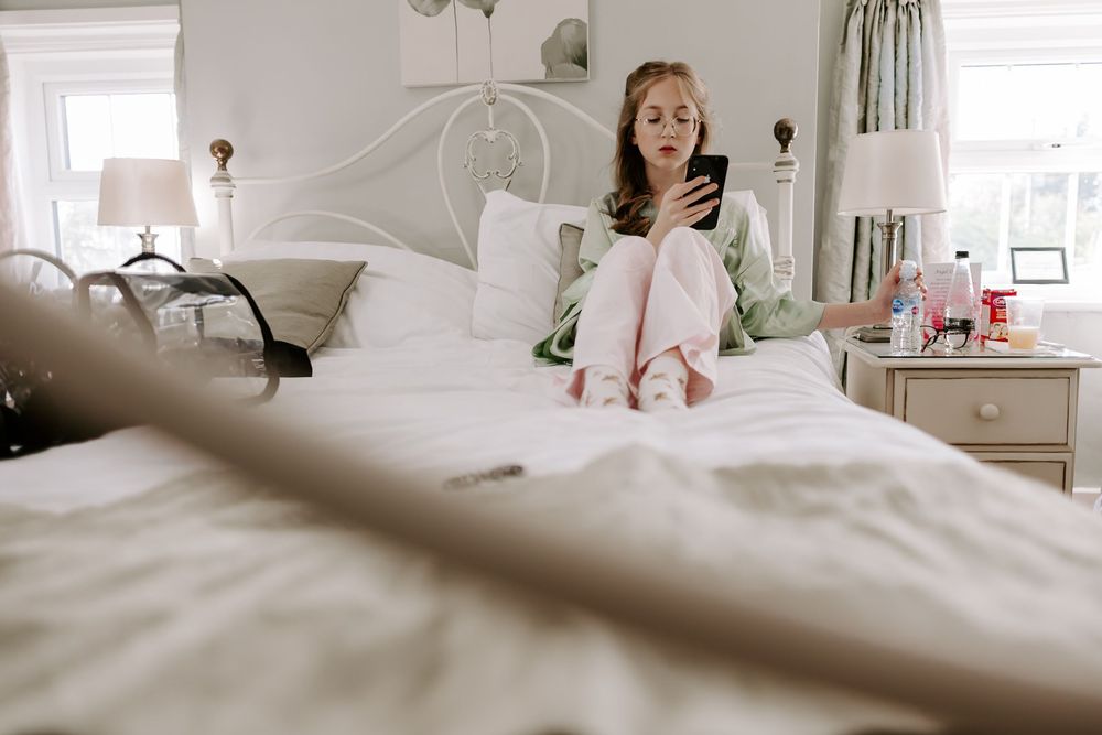 A white and beige bedroom with a metal bed frame, natural light streaming through windows, and cozy bedding.
