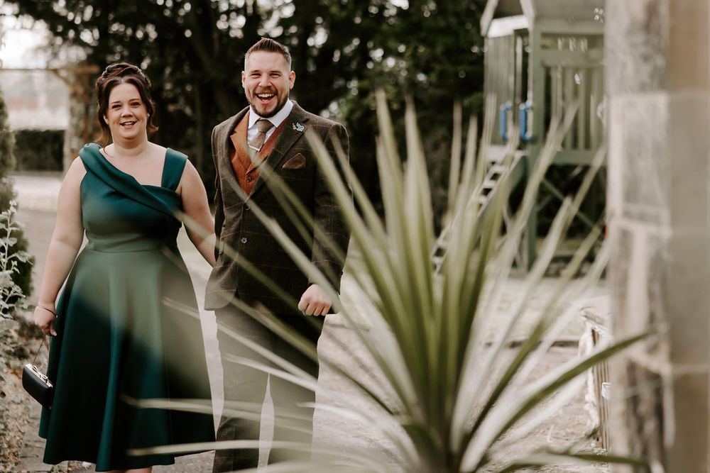 A couple shares a joyful moment together during a garden wedding ceremony surrounded by tropical plants.