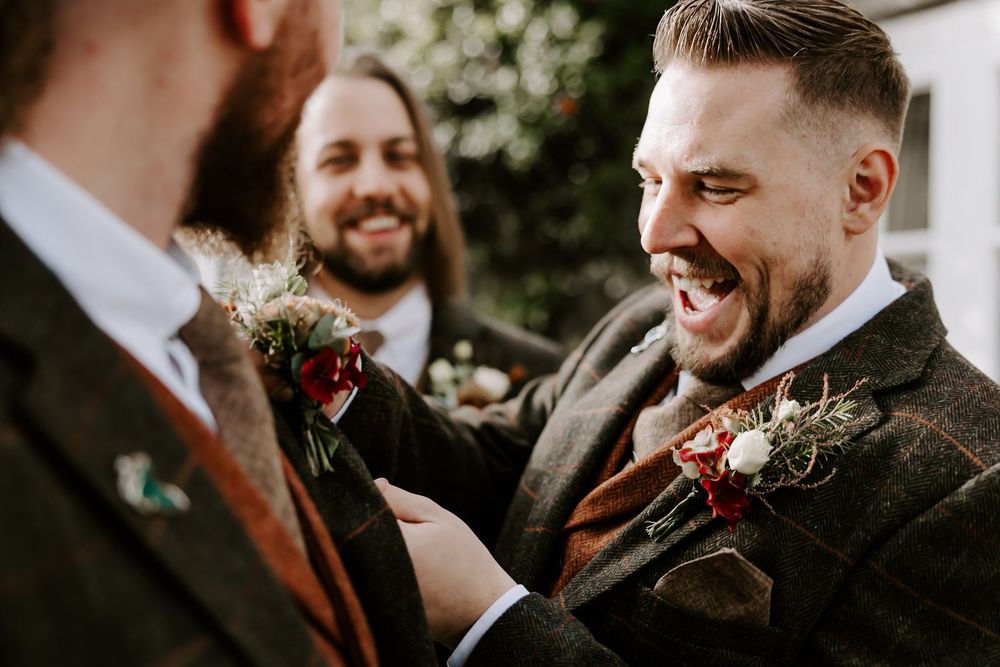 A group of people in formal attire laugh and smile together during a wedding celebration.