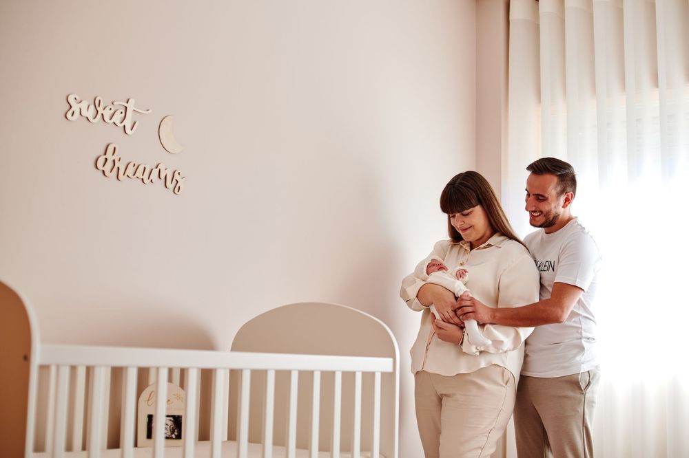Happy parents admiring their newborn baby in a beautifully decorated nursery room.