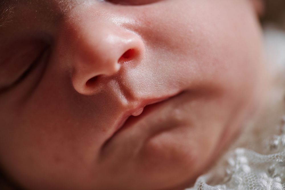 Extreme close-up macro shot of a sleeping newborn baby's nose and lips.