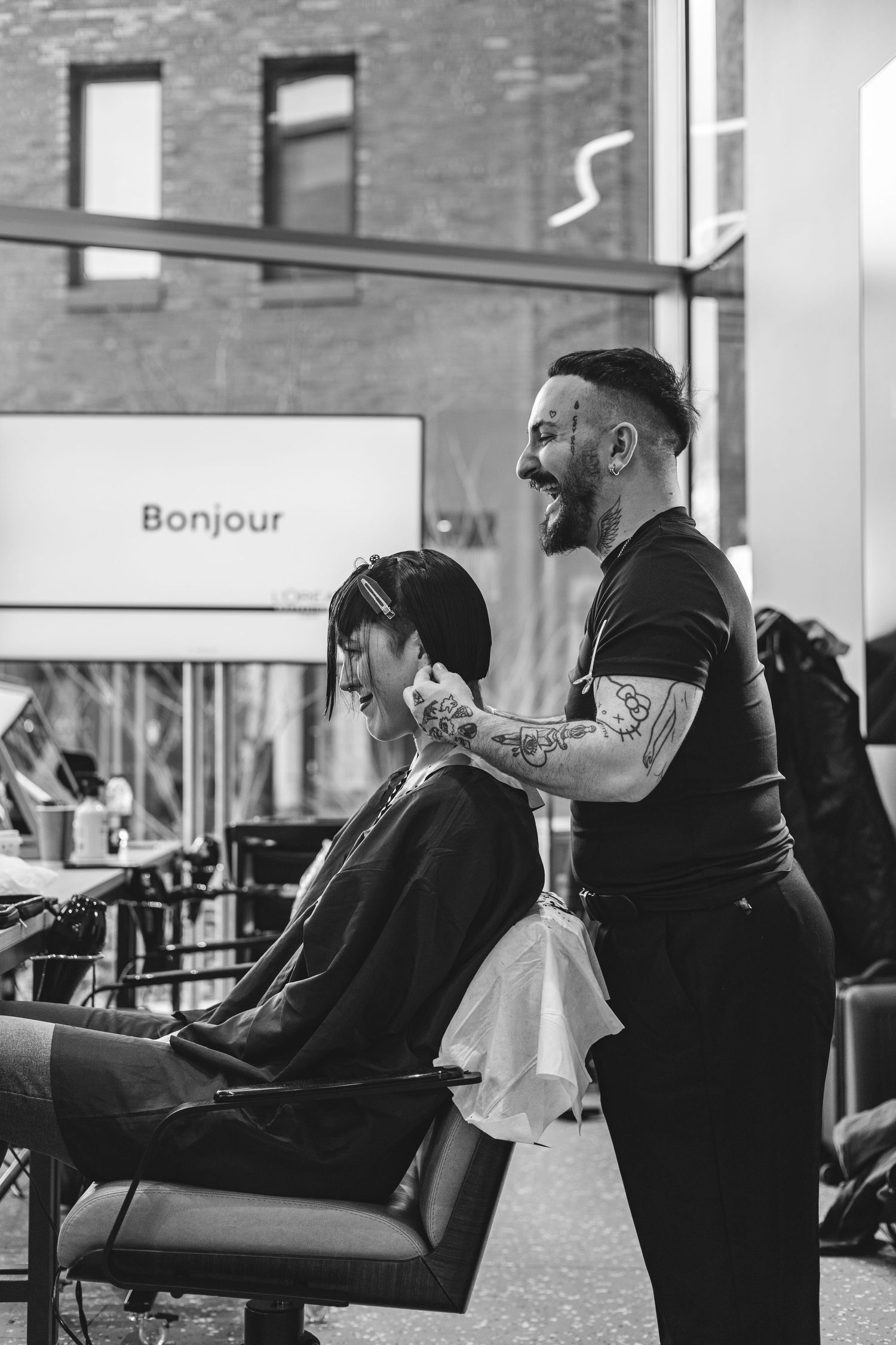 A black and white photo series showing a barber giving a haircut to a client in a modern barbershop setting.