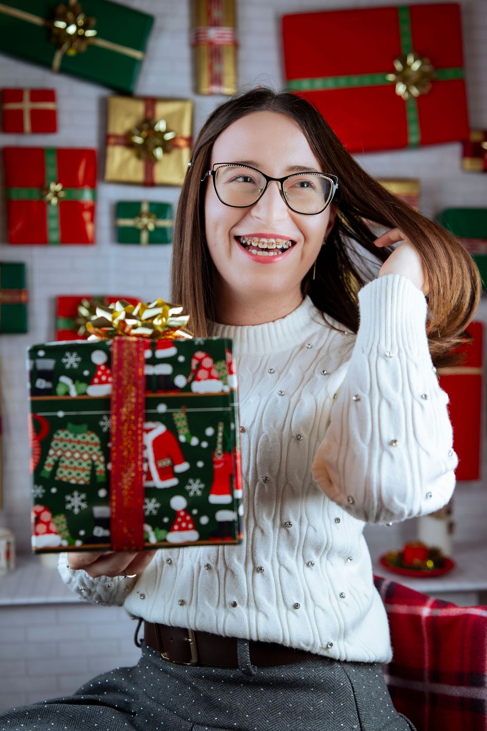 White knit sweater and holiday decorations with red and green wrapped presents in background.