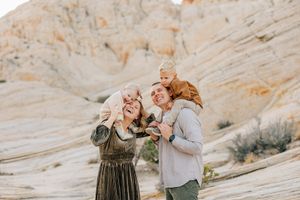 Sweet family interactions captured on smooth desert rock formations during sunset.