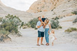 A family shares a tender moment while exploring desert rock formations at sunset.