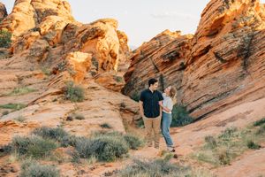 People exploring red rock formations in a desert landscape.