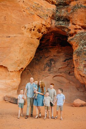 Family standing together inside natural red rock cave formation in Snow Canyon.