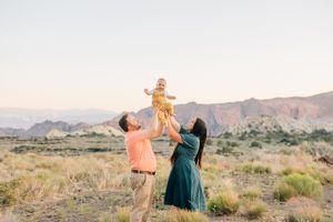 Family members pose in desert landscape with mountains in background during golden hour.