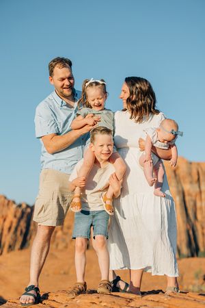Family sharing joyful moments together on red desert rocks during sunset.