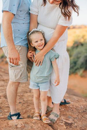 Close-up view of family feet walking together on red desert sand.