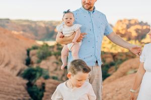 Family enjoying a playful moment together against desert rock formations at sunset.