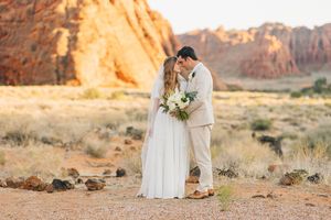 A couple shares an intimate moment among the red rocks during golden hour.