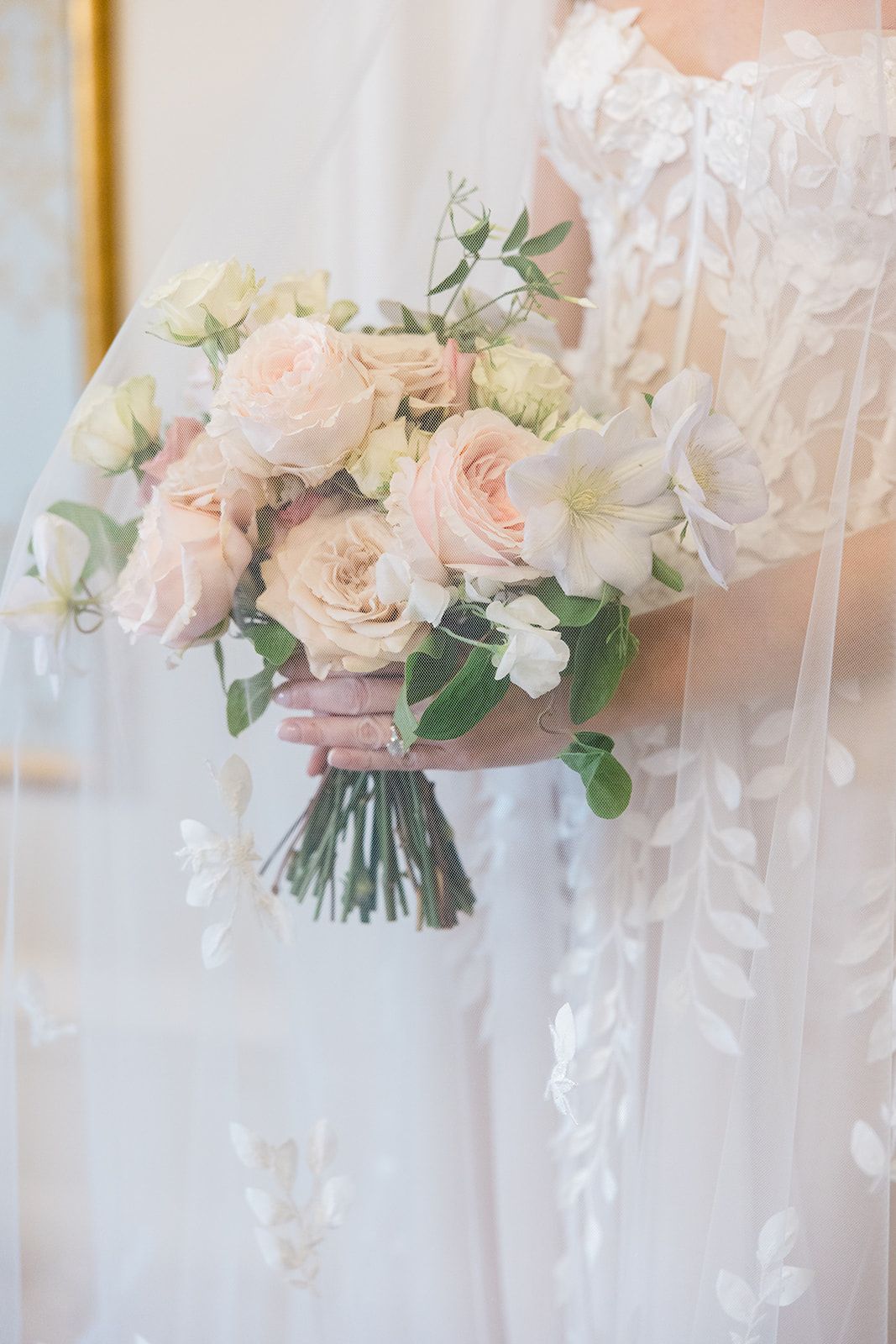 Beautiful wedding bouquet with blush pink roses and white flowers tied with delicate ribbons in an elegant setting.