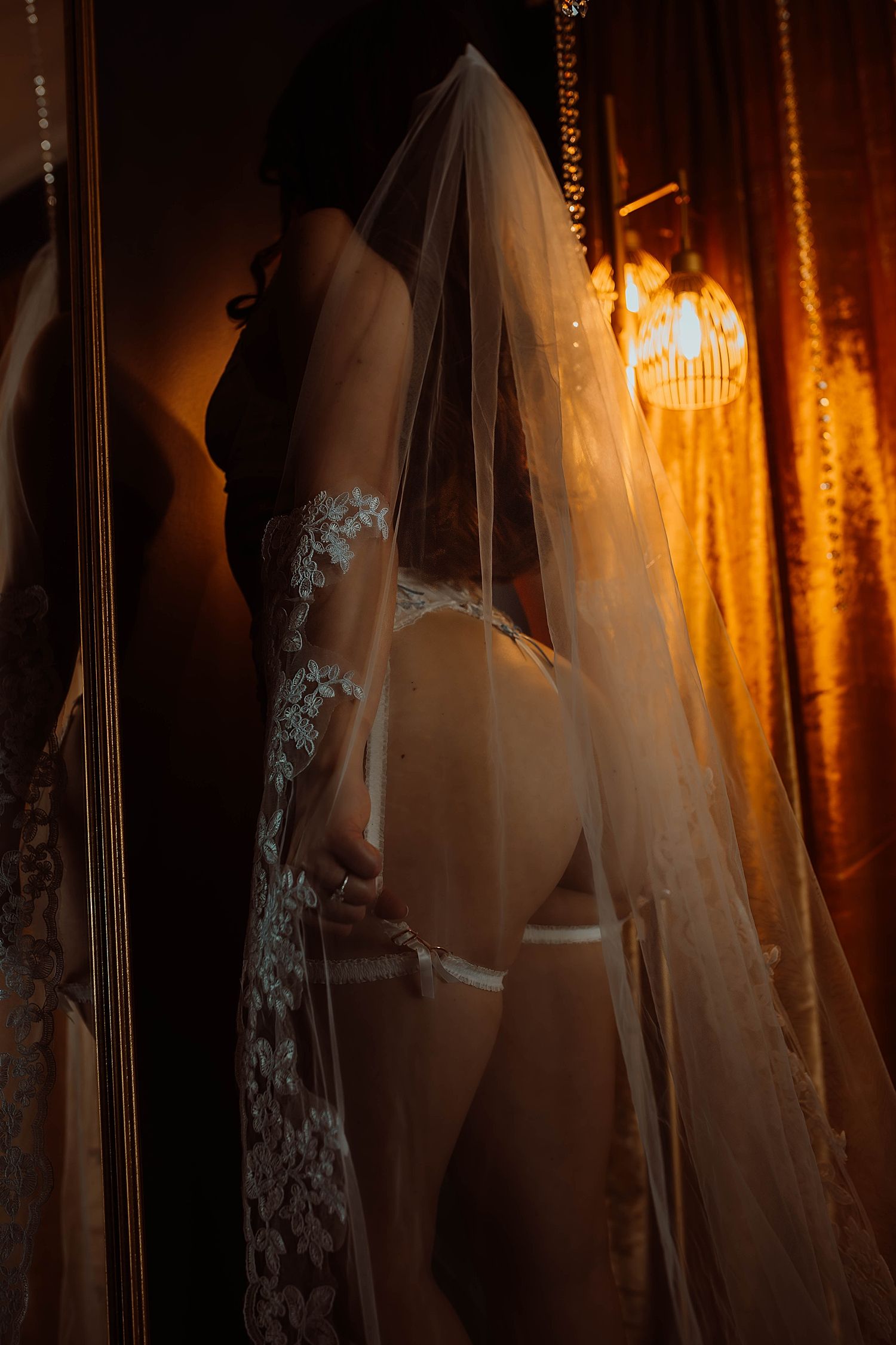 person in lace veil leans against the mirror showing why all brides need a boudoir experience
