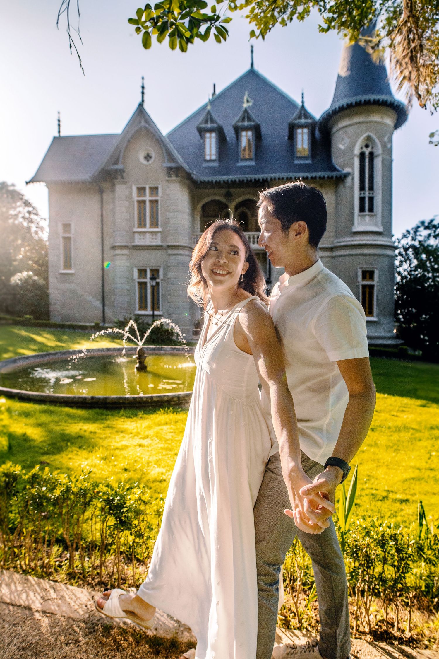 A couple in white enjoying a romantic moment against sunset light near a beautiful chateau in France.