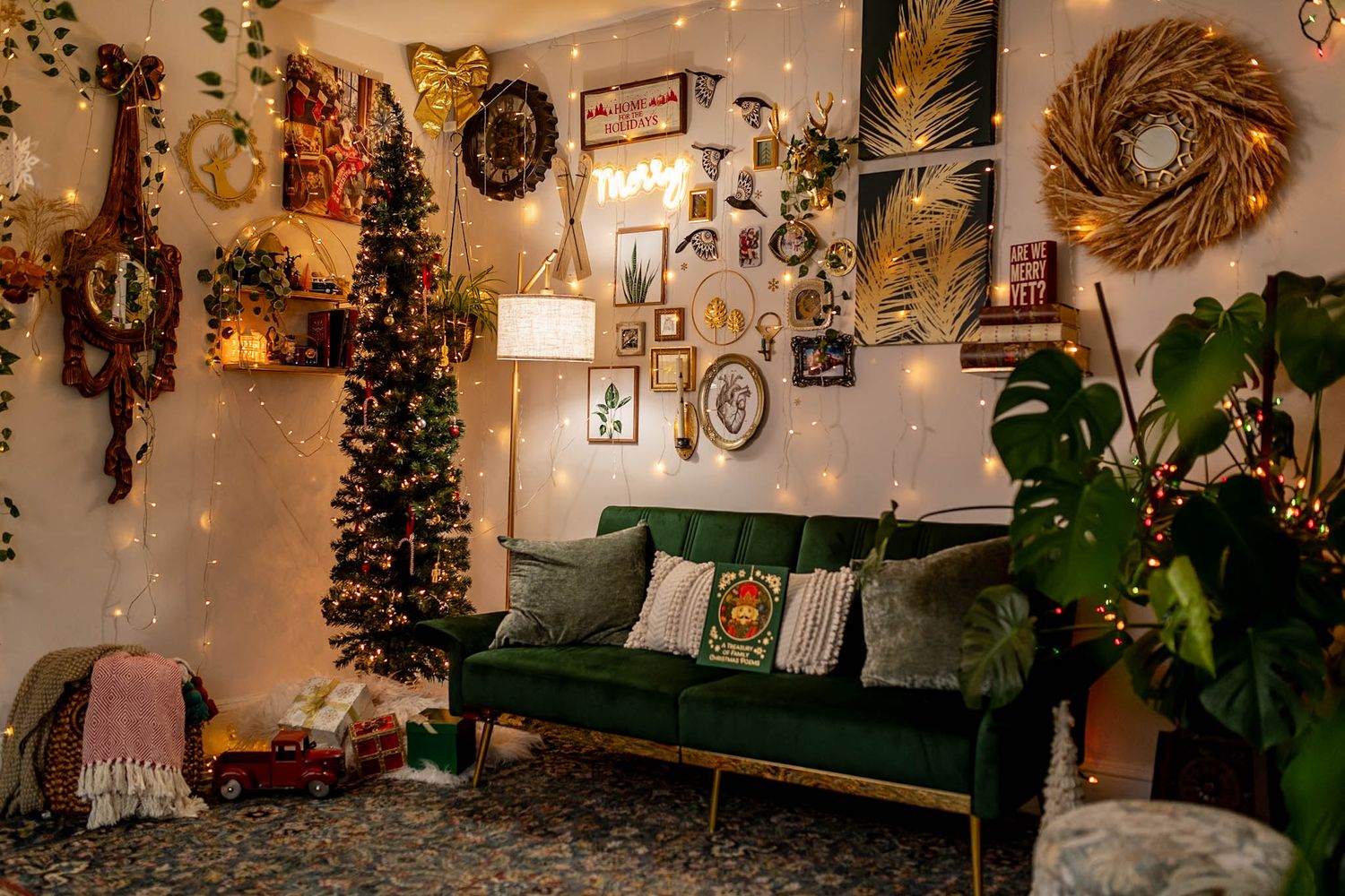 Cozy living room decorated for Christmas with a green velvet couch, wall art, and twinkling lights.