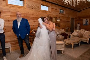 Bride hugging her mom while her dad stands nearby inside The Barn at Lakeside Ranch before the wedding ceremony..
