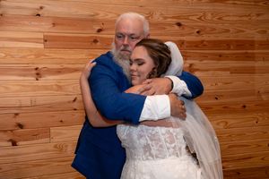 Emotional moment of the bride hugging her father inside The Barn at Lakeside Ranch during her wedding day.