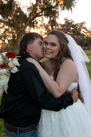 Romantic sunset wedding portrait showing a couple sharing an intimate moment with a beautiful floral bouquet.