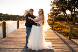 Romantic sunset photoshoot on wooden dock with golden light reflecting off lake.