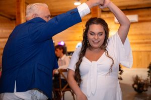 A dad and daughter  dance together during a wedding celebration in a rustic wooden venue.