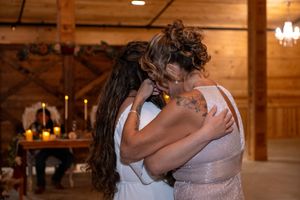 Bride and her mom sharing an emotional hug during their mother–daughter dance inside The Barn at Lakeside Ranch.