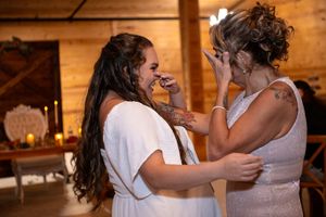 Bride smiling and crying emotionally with her mom during their mother–daughter dance at The Barn at Lakeside Ranch wedding reception.