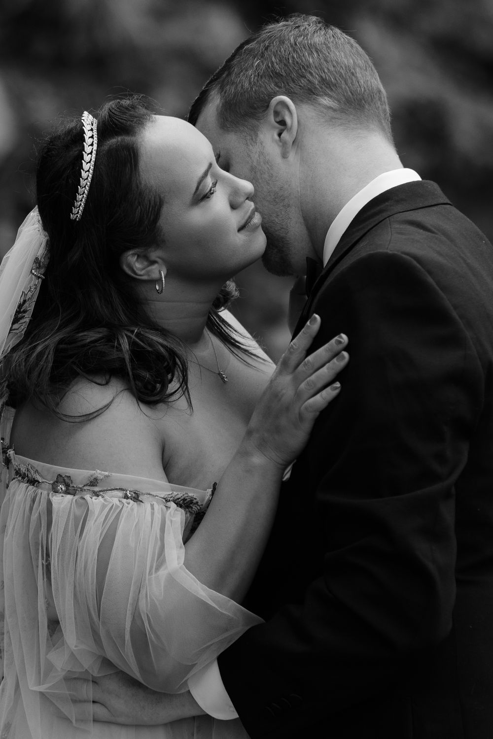 A romantic black and white photo series showing a couple sharing intimate kisses at their wedding celebration.