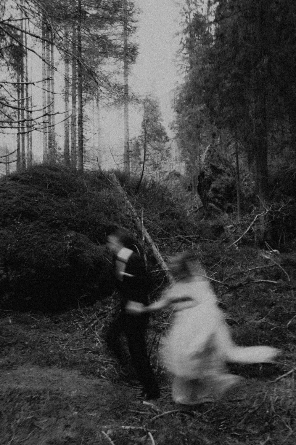 A blurred sequence of movement captured in black and white shows figures in motion against a forest backdrop.