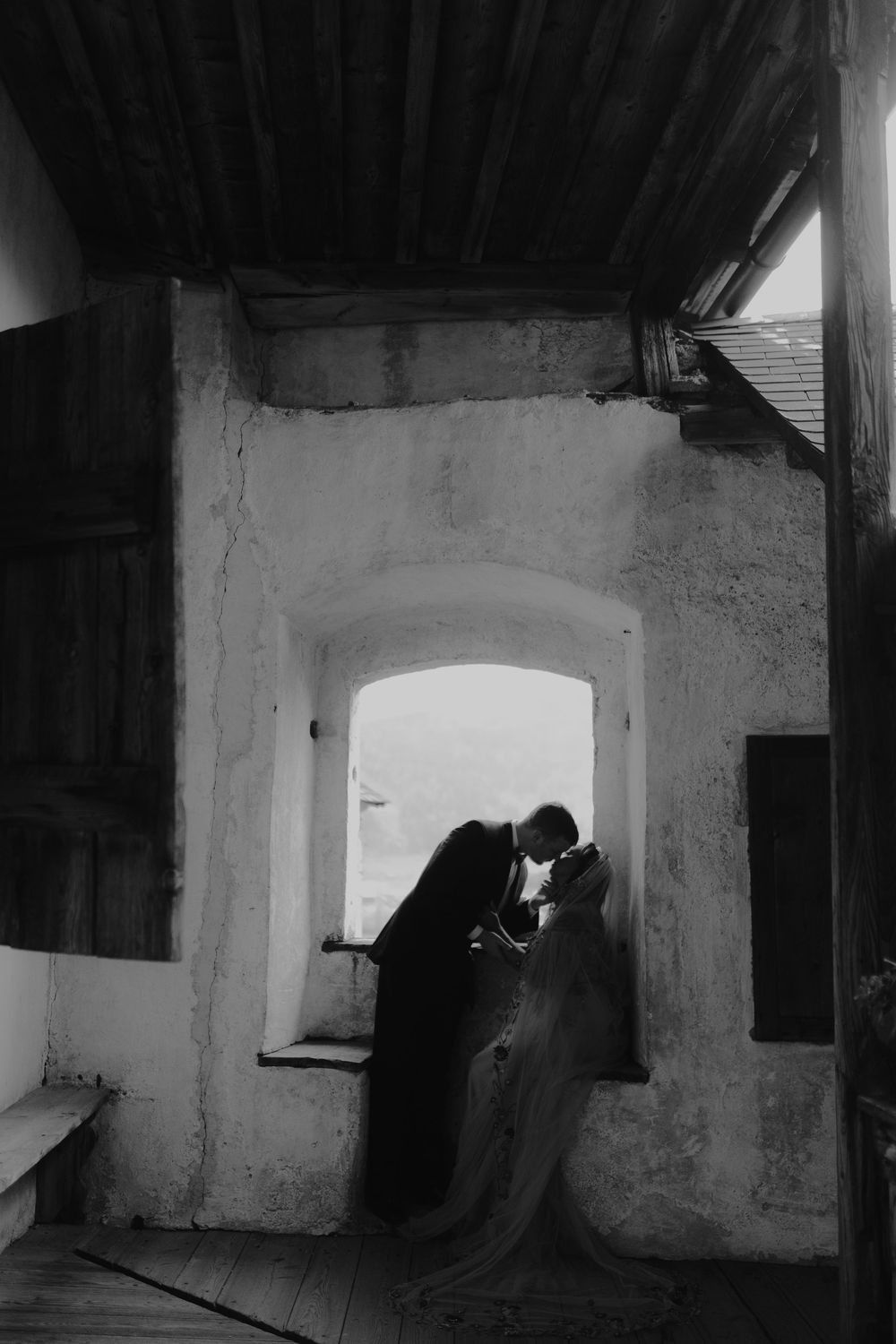 Dark interior of stone building with arched doorway and dramatic shadows.