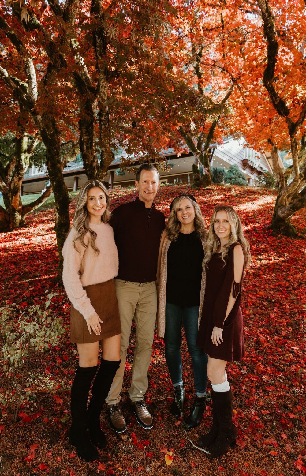 Group standing together under vibrant red autumn maple trees in a park setting during fall season.