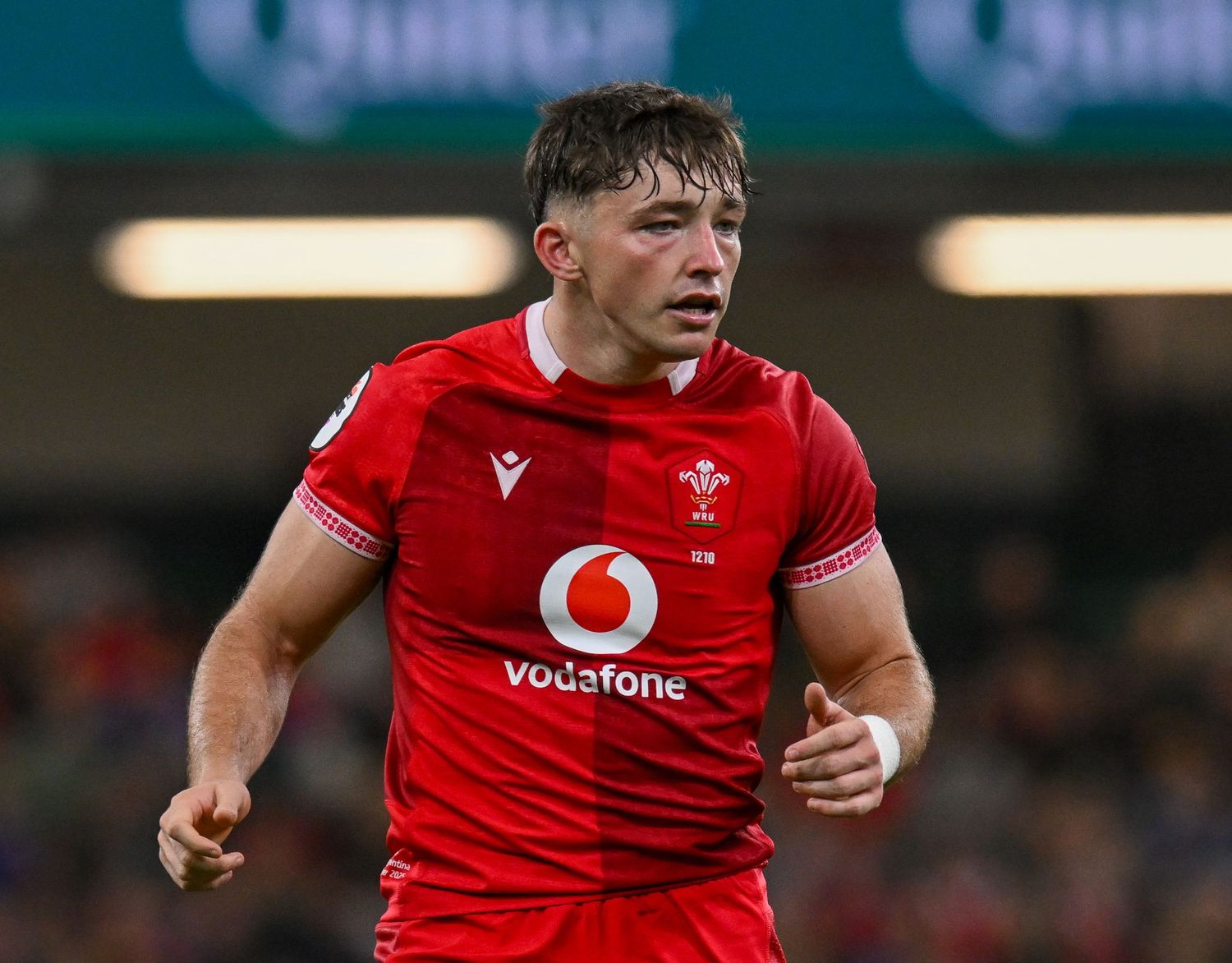 Rugby players in red Welsh jerseys running on the field during an international match.
