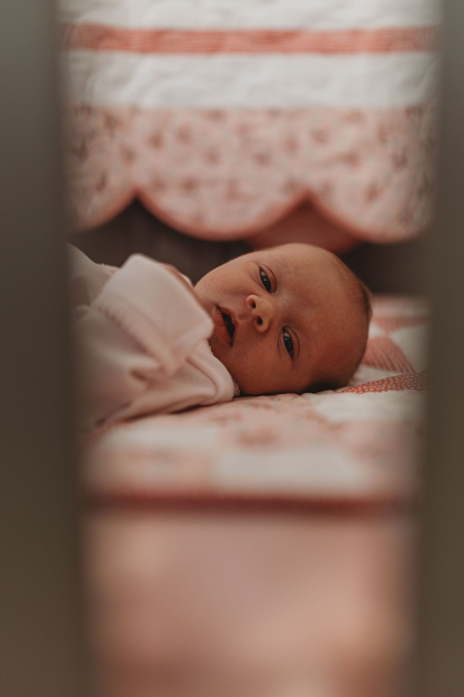 Newborn baby resting peacefully on soft bedding in natural light.