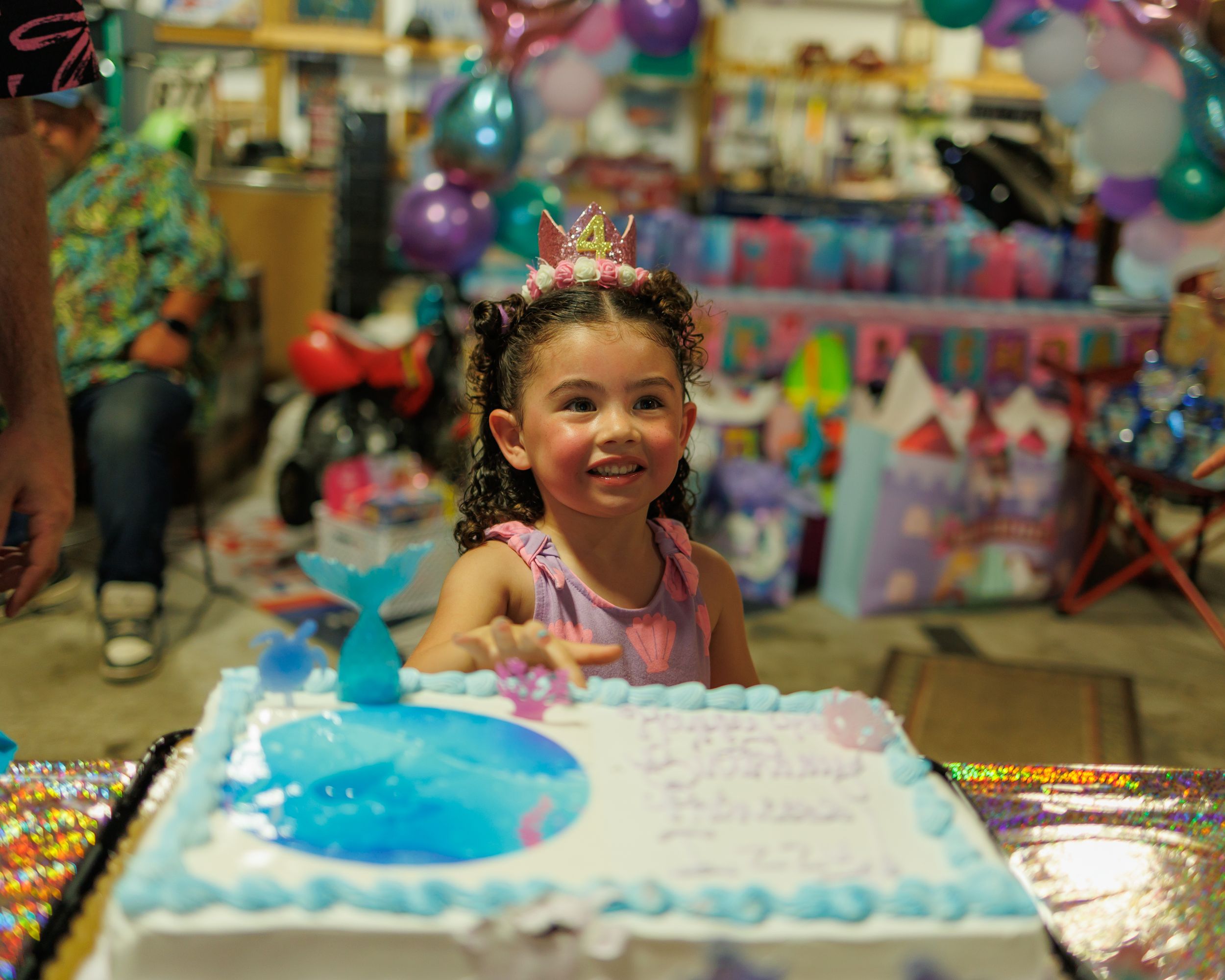 A birthday celebration features a bright blue cake with white frosting and colorful decorations at a festive party.