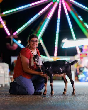 A series of photos showing someone posing with a black dog against a colorful illuminated carnival backdrop at night.