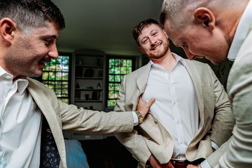 Three people in white dress shirts share a candid laughing moment together during a celebration.