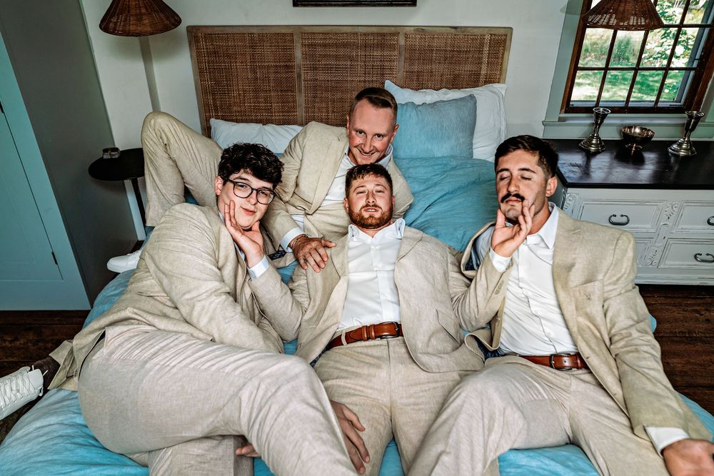 Several people relax together on a couch wearing matching beige suits in a casual indoor setting.