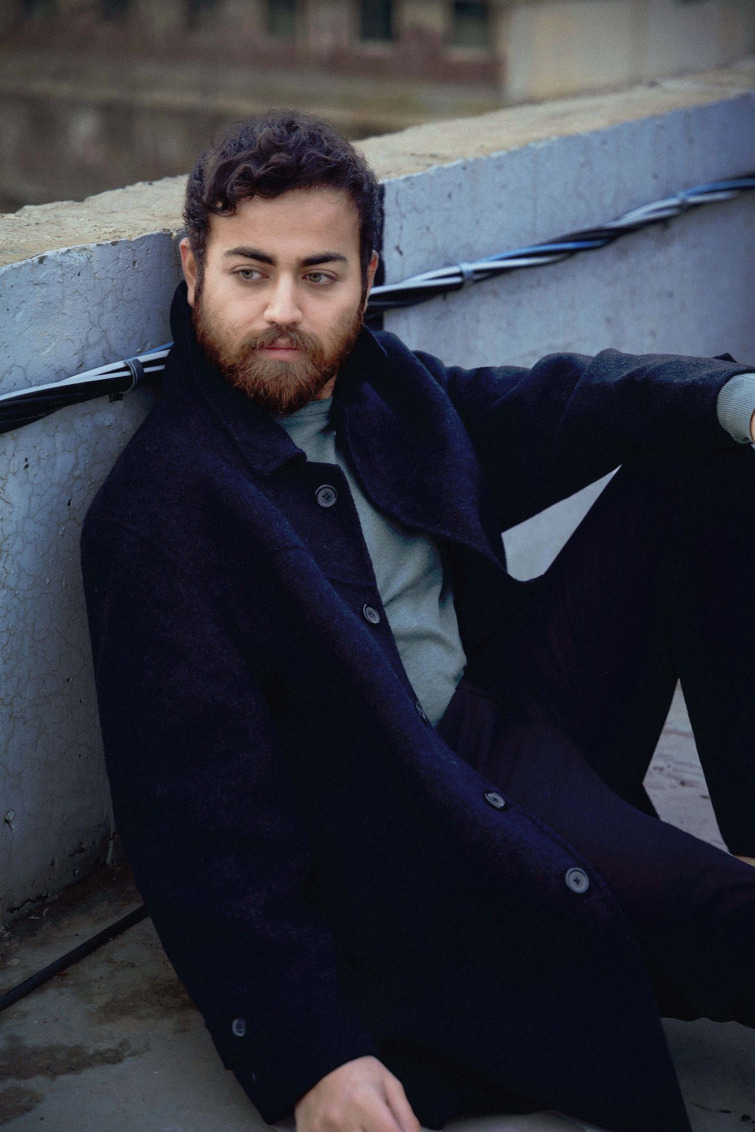 A person wearing a navy blue jacket reclines against a concrete surface in a series of similar poses.