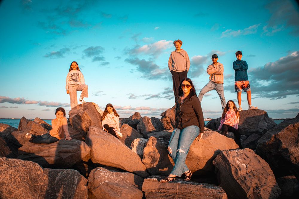 Group of people sitting on large rocks at sunset in a beach landscape enjoying the scenic view.