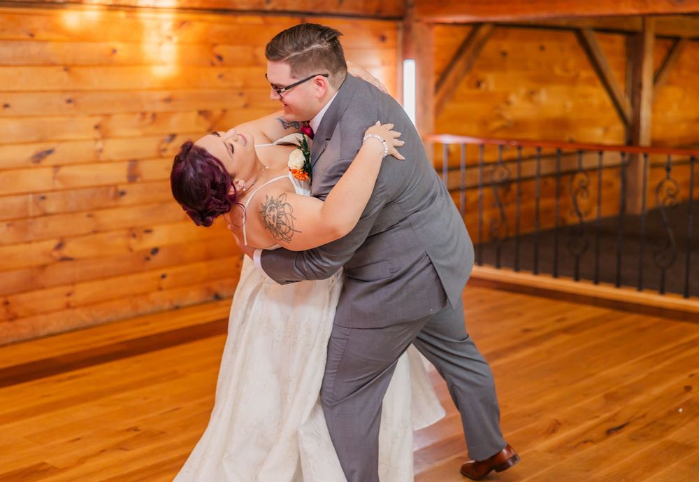 Couples dancing together on a wooden dance floor at an indoor wedding reception.