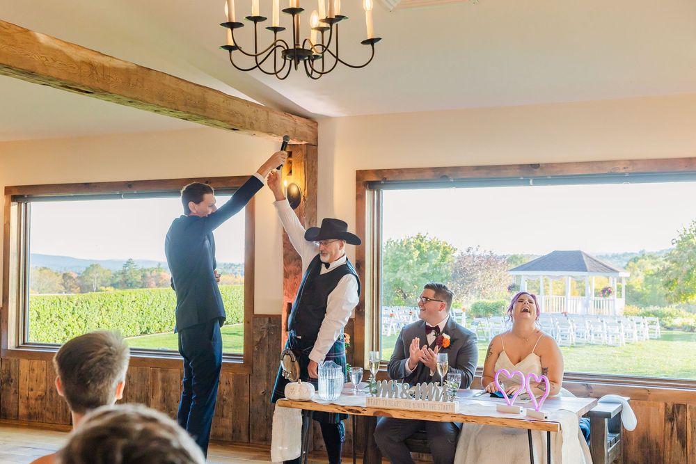 Wedding reception celebration in a bright venue with large windows overlooking outdoor scenery.