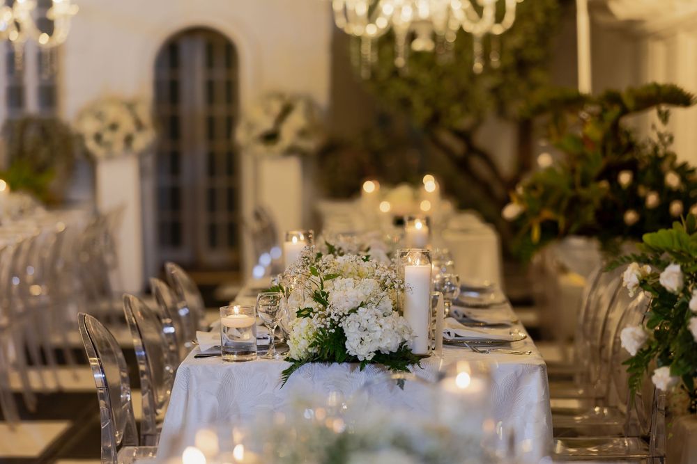 Luxurious wedding reception setup with golden lighting, white tablescapes, and ornate architectural details.