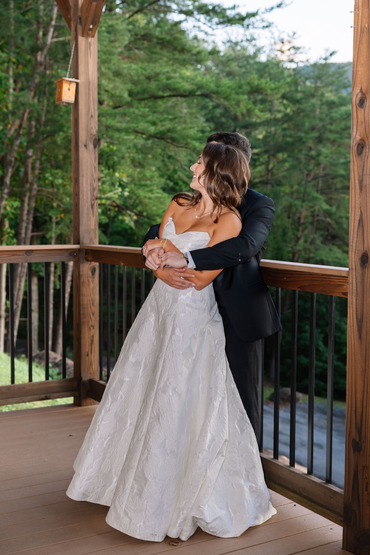 A series of four photos showing a bride in a white gown sitting on a wooden deck overlooking a forest landscape.