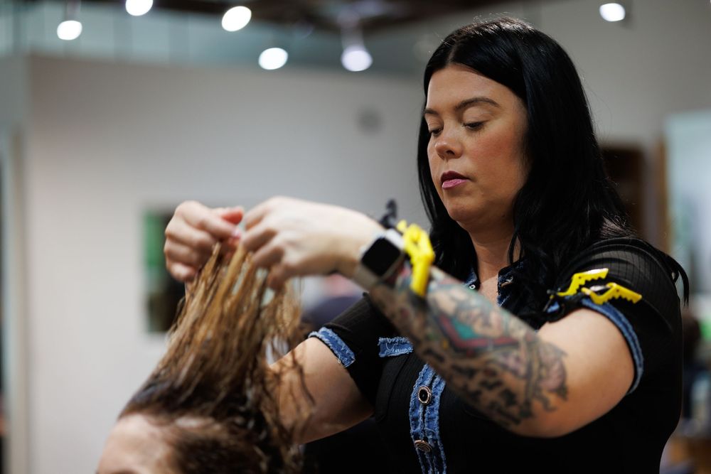 Hairstylist performing detailed styling work in modern salon setting.