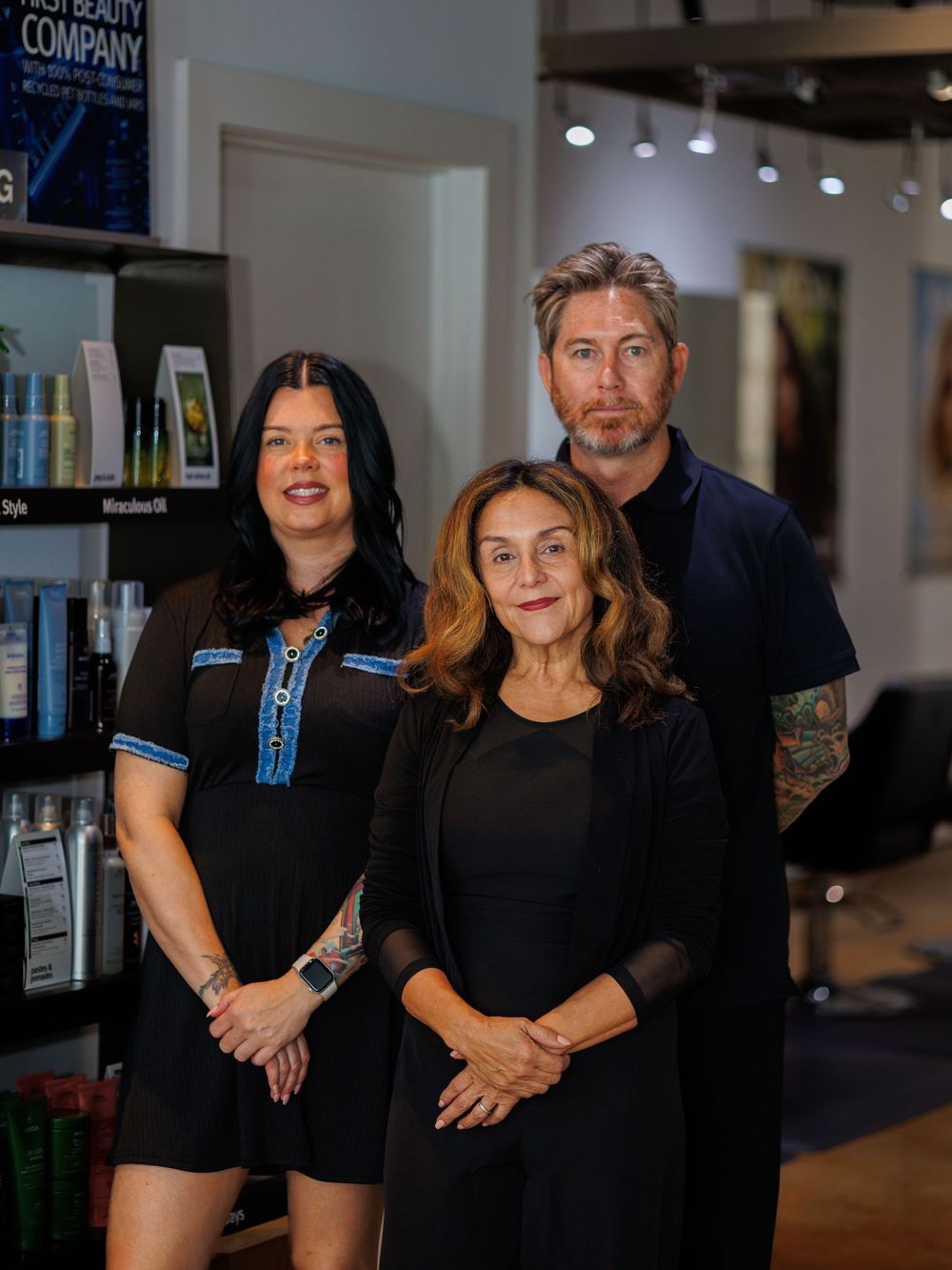 Beauty professionals gathered for a group photo in their salon wearing matching black outfits.