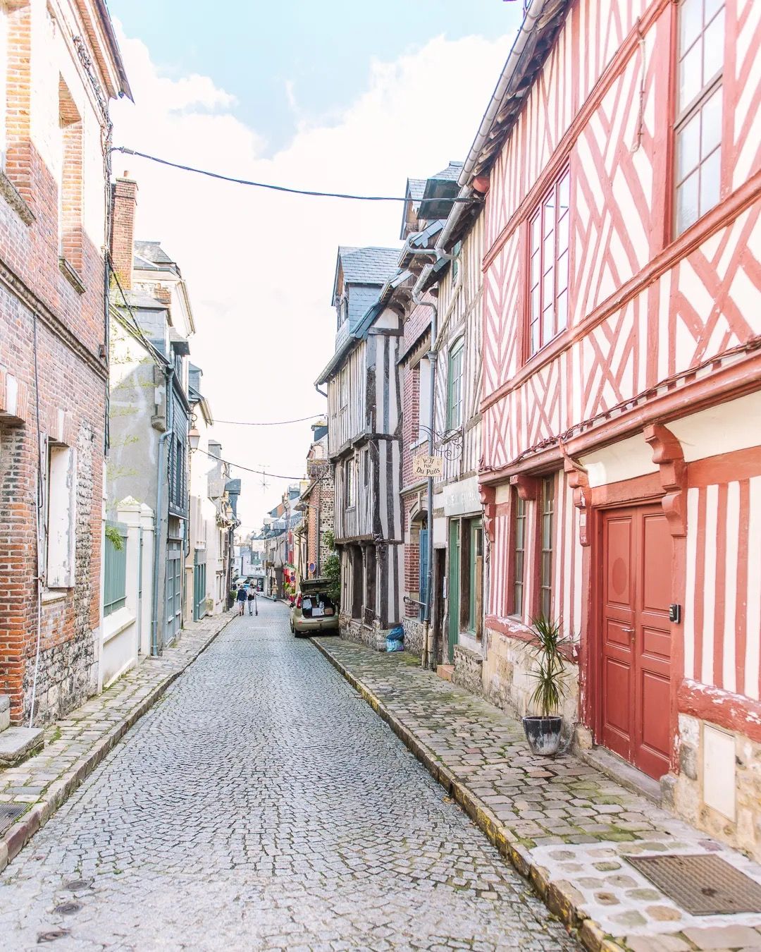 Colourful timber-frame buildings lining a narrow cobbled street in a historic town.