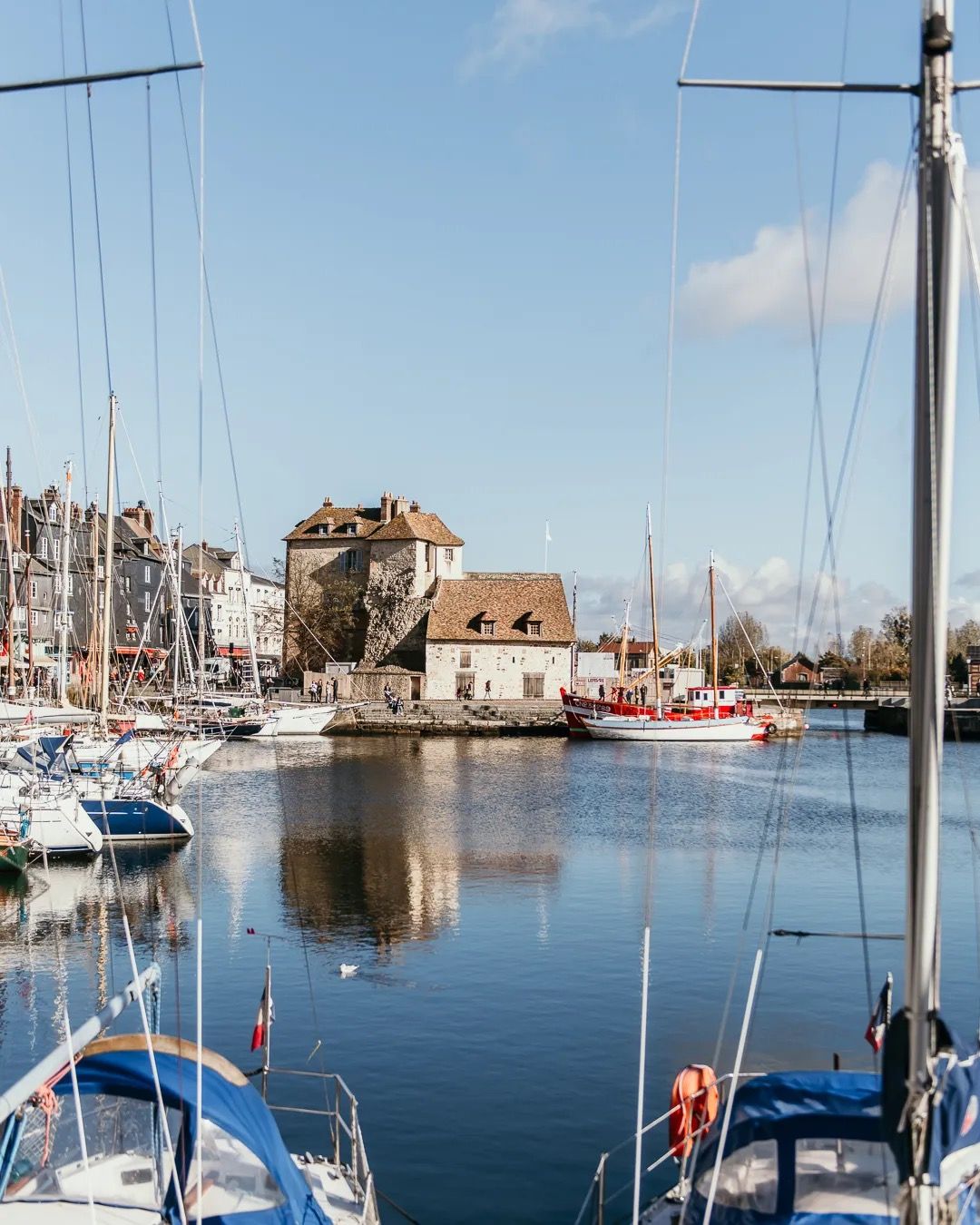 Sailboats in a quiet harbour with soft warm light reflecting on the water.