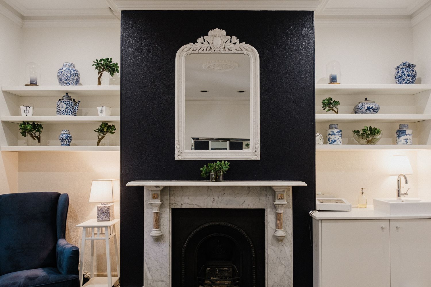 Modern living room features a sleek black accent wall with white built-in shelving and decorative blue pottery accents.