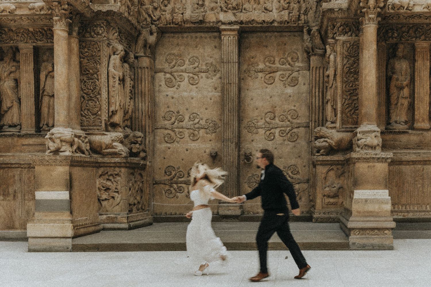 A couple performs a graceful dance move in front of an ornate stone building with classical architecture.