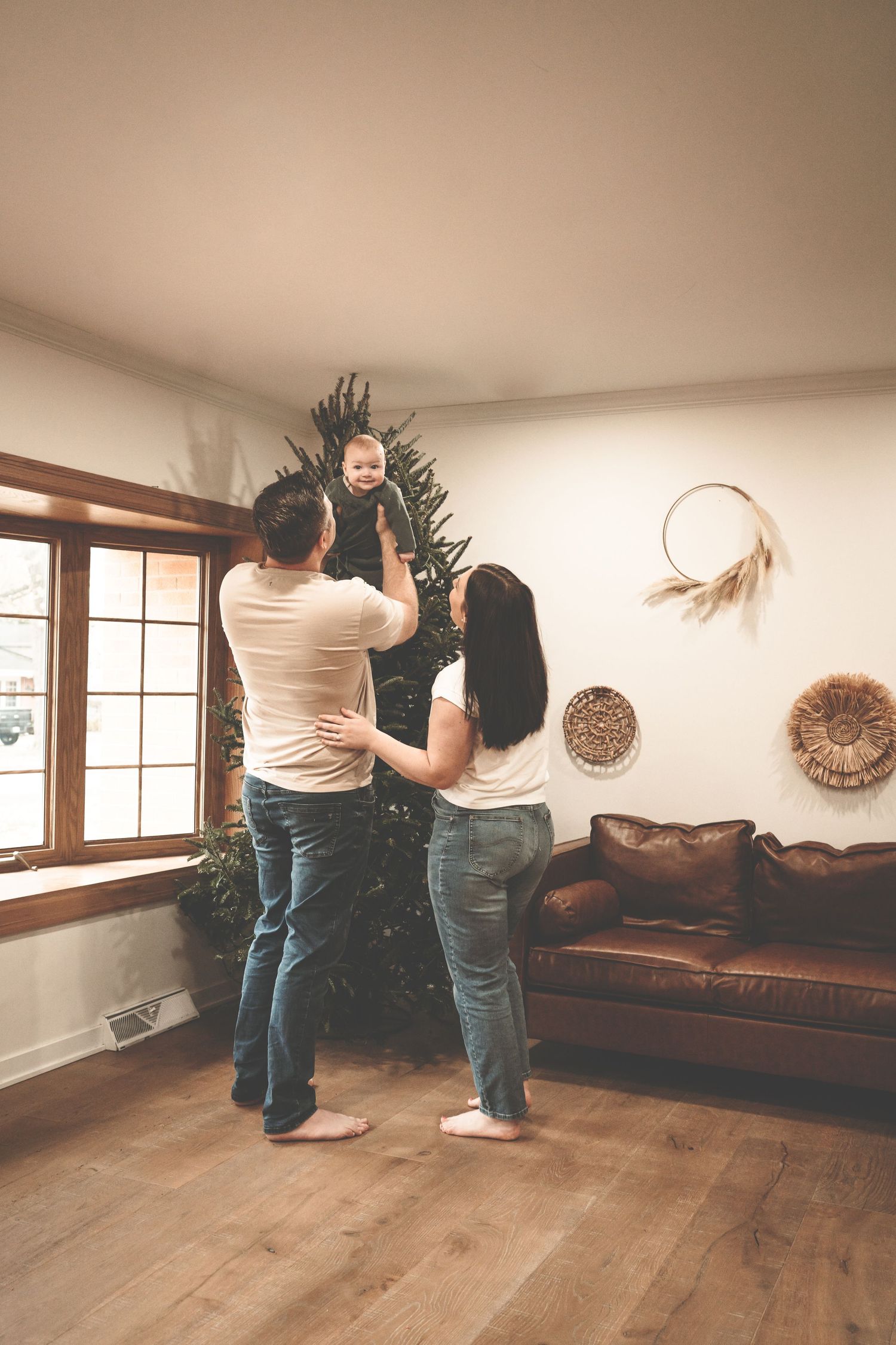 Family decorating Christmas tree together in cozy living room with hardwood floors and rustic wall decor in Arlington Heights